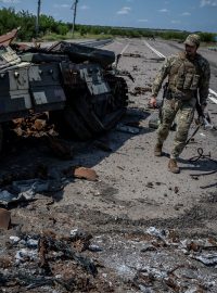 Ukrajinský voják prochází kolem zničeného tanku