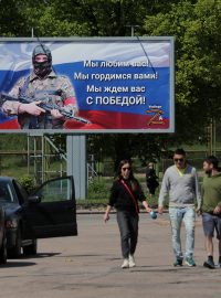 Lidé ve městě Vyborg v Leningradské oblasti procházejí kolem billboardu, na kterém je napsáno: „Milujeme vás! Jsme na vás hrdí! Čekáme na vás s vítězstvím!“ (archivní foto)
