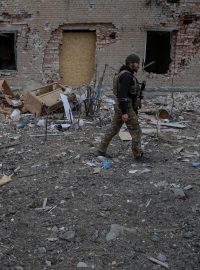 Ukrajinský voják prochází kolem zničených budov ve městě Časiv Jar poblíž frontové linie