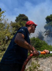 Hasič se snaží zastavit požár u vesnice Vasilika na řeckém ostrově Evia