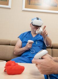 Lékaři v modrých pláštích si těsně před zákrokem nasazují bílé brýle pro virtuální realitu
