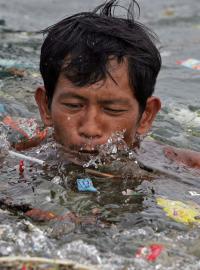 Muž plave v hromadě plastů kumulujících se v moři
