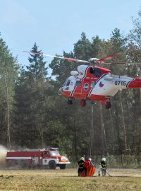 Hasiči plní vodou vak, z kterého za pomoci vrtulníku hasí požáry mezi Bakovem nad Jizerou a Bělou pod Bezdězem na Mladoboleslavsku.