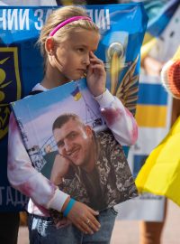 Dcera ukrajinského válečného zajatce drží portrét svého otce během shromáždění požadujícího urychlení výměny zajatců
