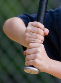 Dítě drží v ruce baseballovou pálku