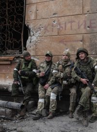 ruští vojáci odpočívají u zničené budovy v Mariupolu