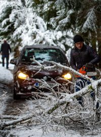 Muž odstraňuje větev zlomenou tíhou sněhu na cestě poblíž Bělé na Prachaticku